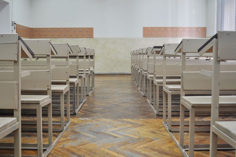 An empty examination hall with rows of single desks, in ink duotone.